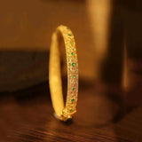 Pulsera tipo brazalete con piedras preciosas verdes doradas y patrón floral en estilo étnico